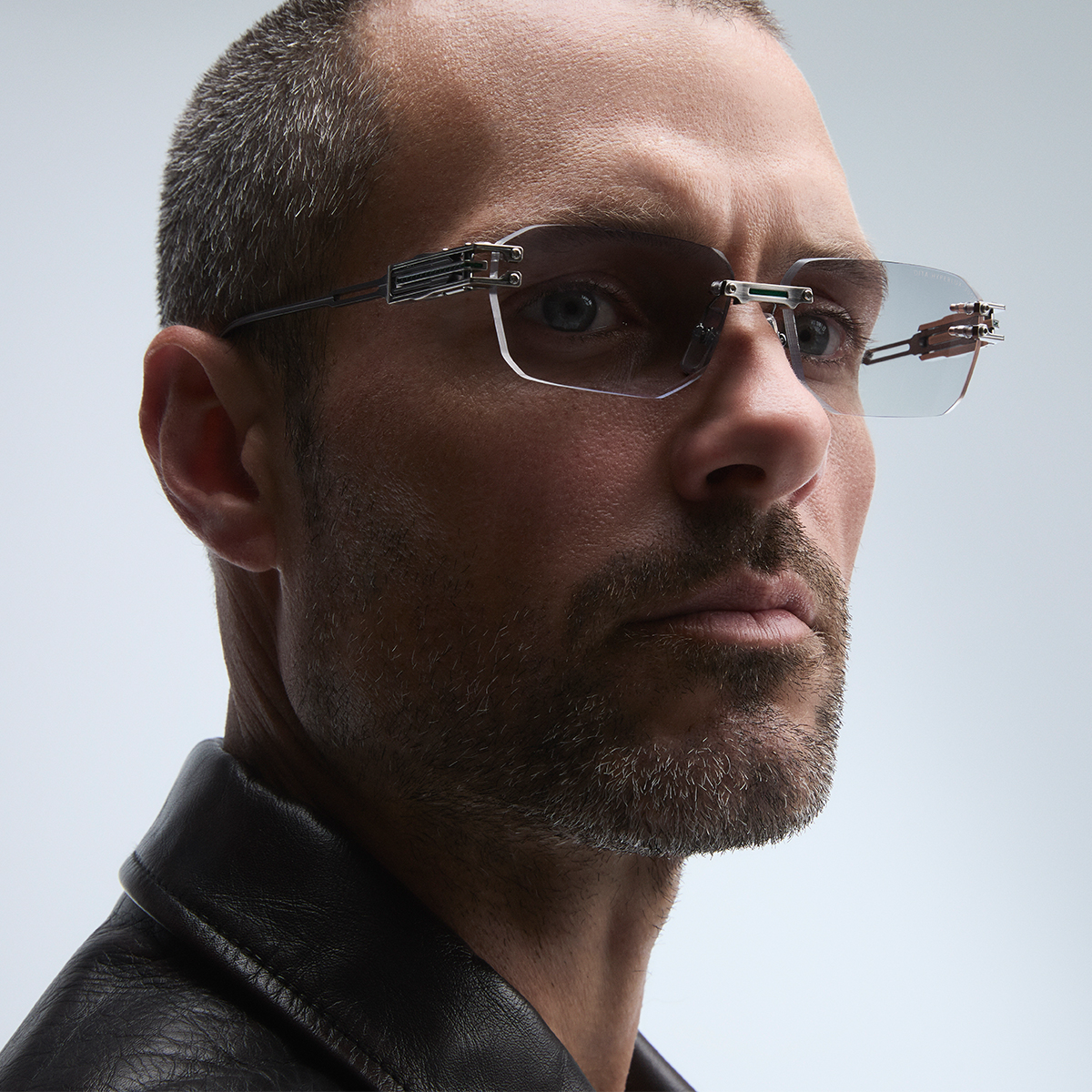 Man with glasses and a leather jacket, looking confidently at the camera.
