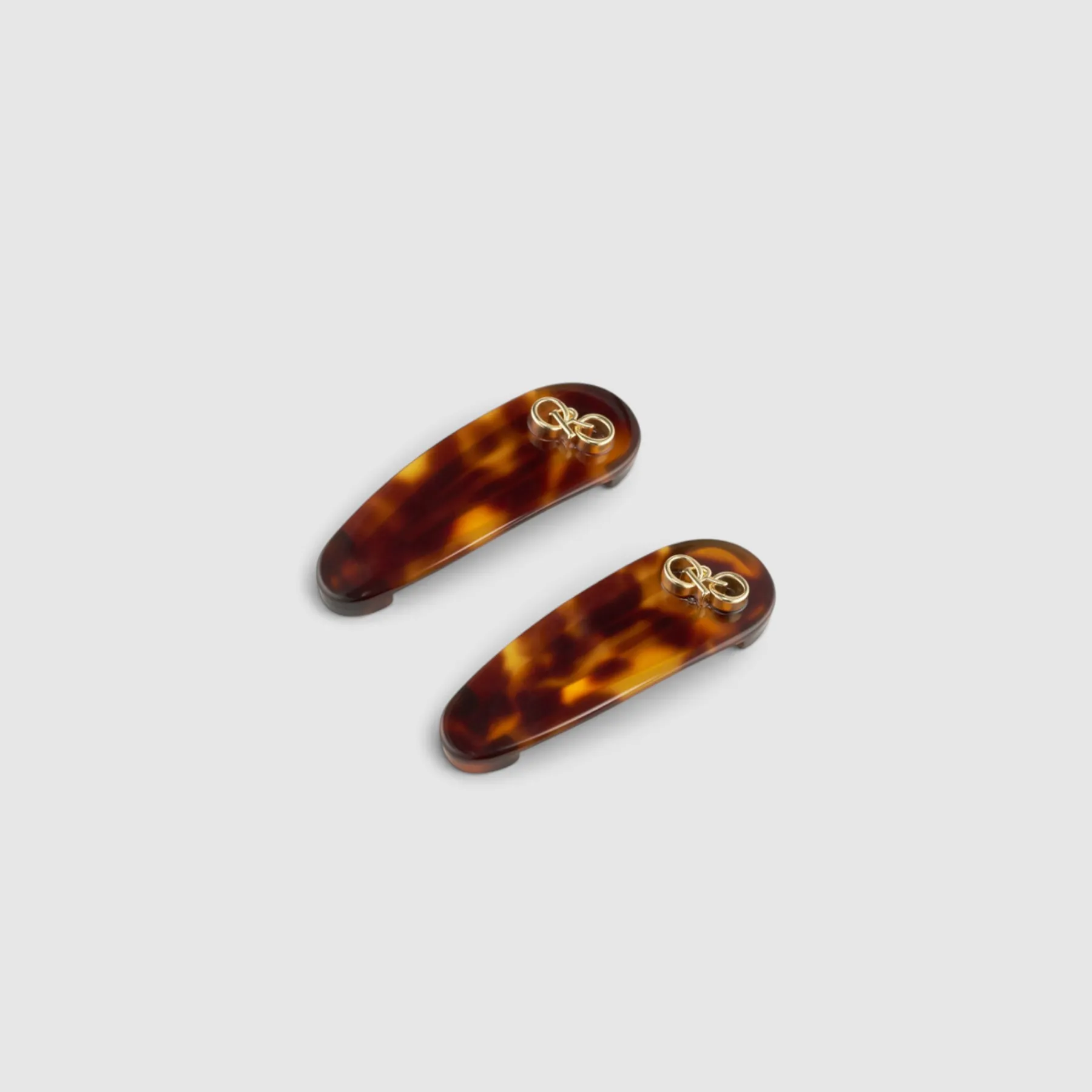 Tortoiseshell hair clips with gold accents on a gray background.