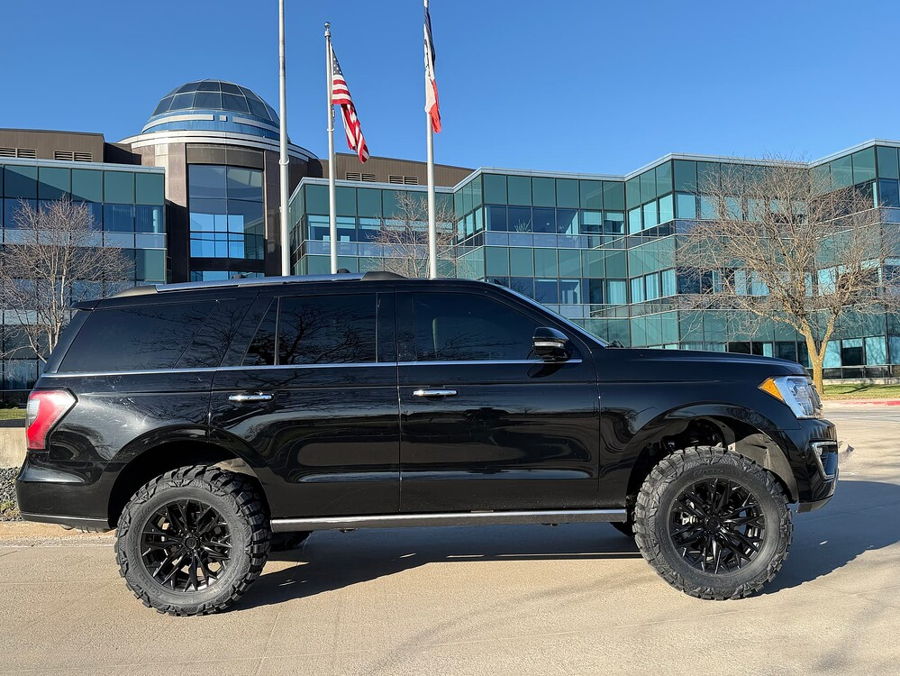 Full side profile Troy's black lifted 2018 Ford Expedition with off-road tires before glass dome office building gallery photo 18