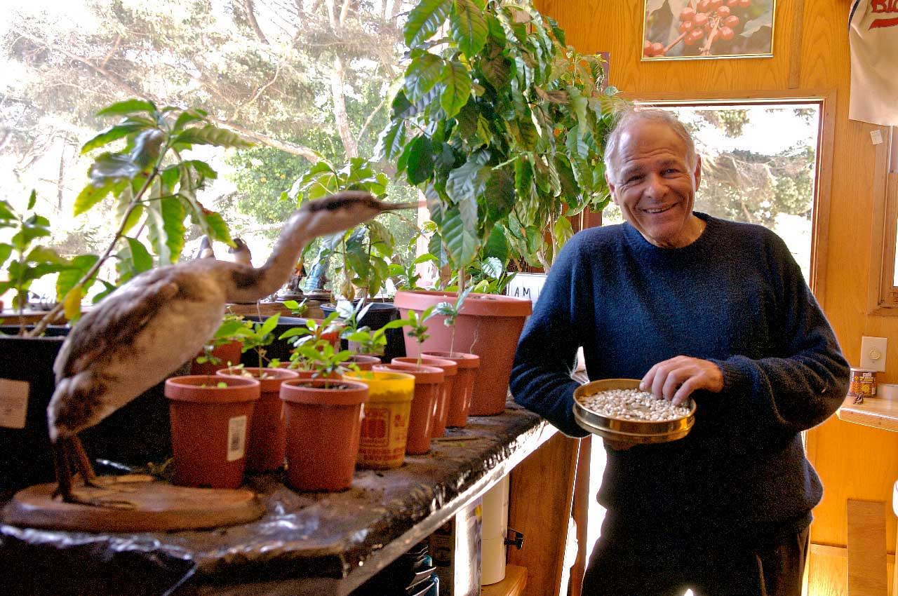 Person smiling near potted plants and a bird statue indoors.