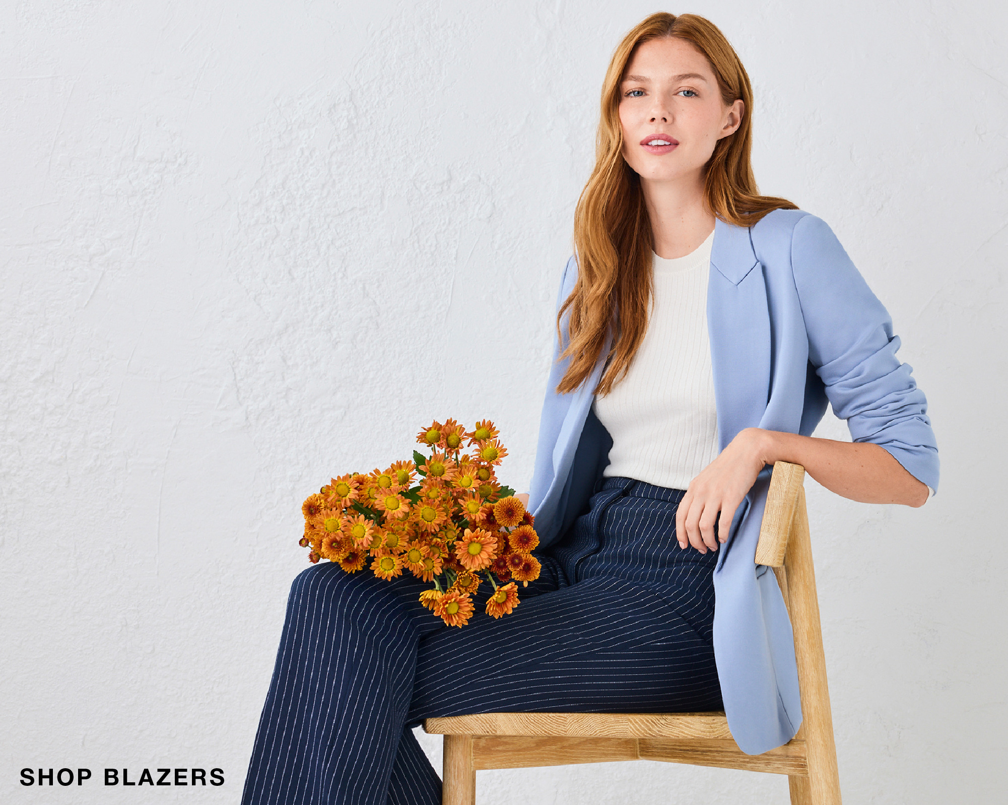 Woman in a blue blazer sitting with flowers on her lap.