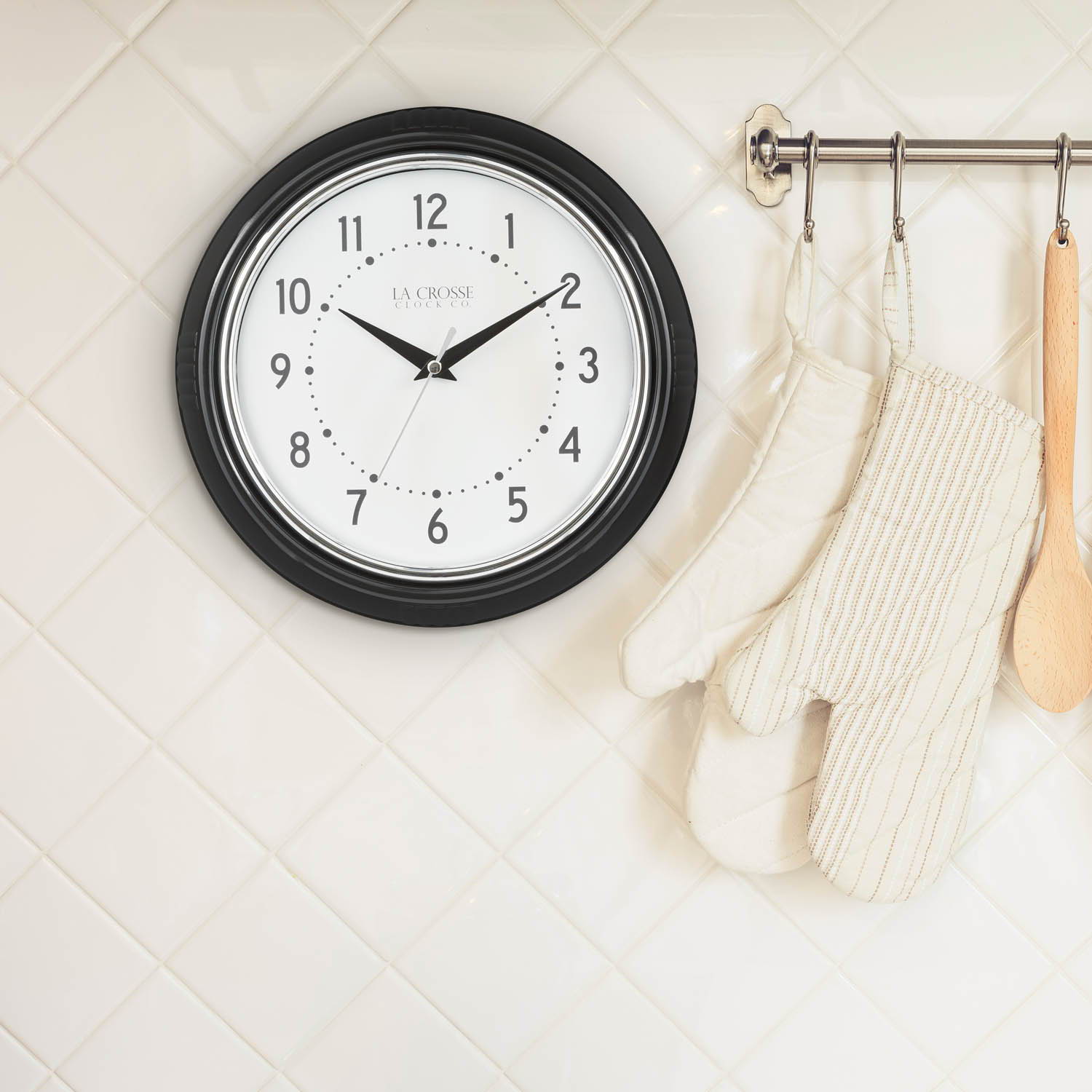 404-3624B Diner Wall clock hanging on a wall with with oven mitts and a wooden spoon hanging nearby.