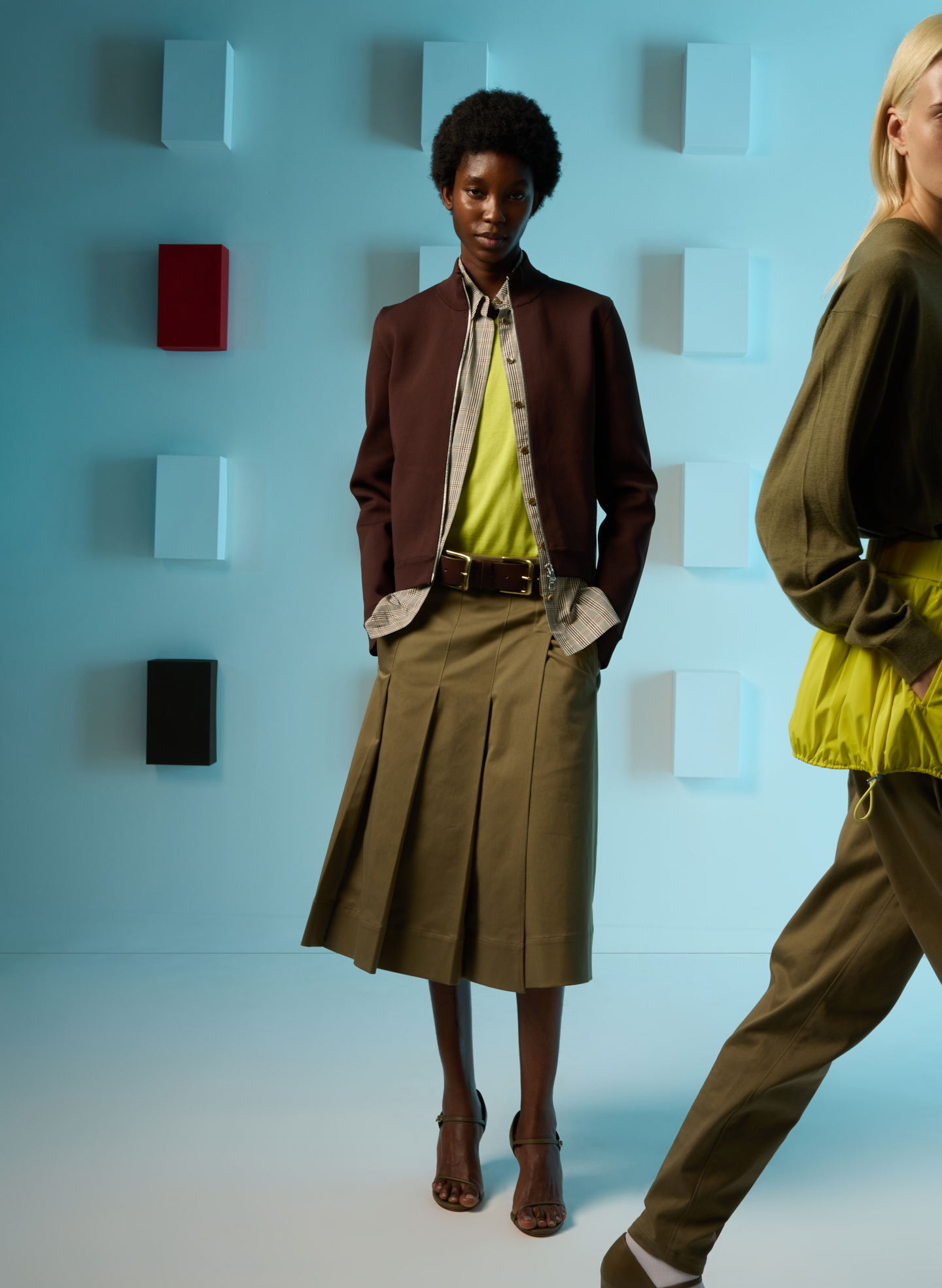 Model in fashionable outfit against a colorful background.