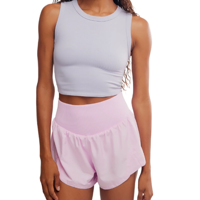 Woman wearing a light gray crop top and pink shorts.