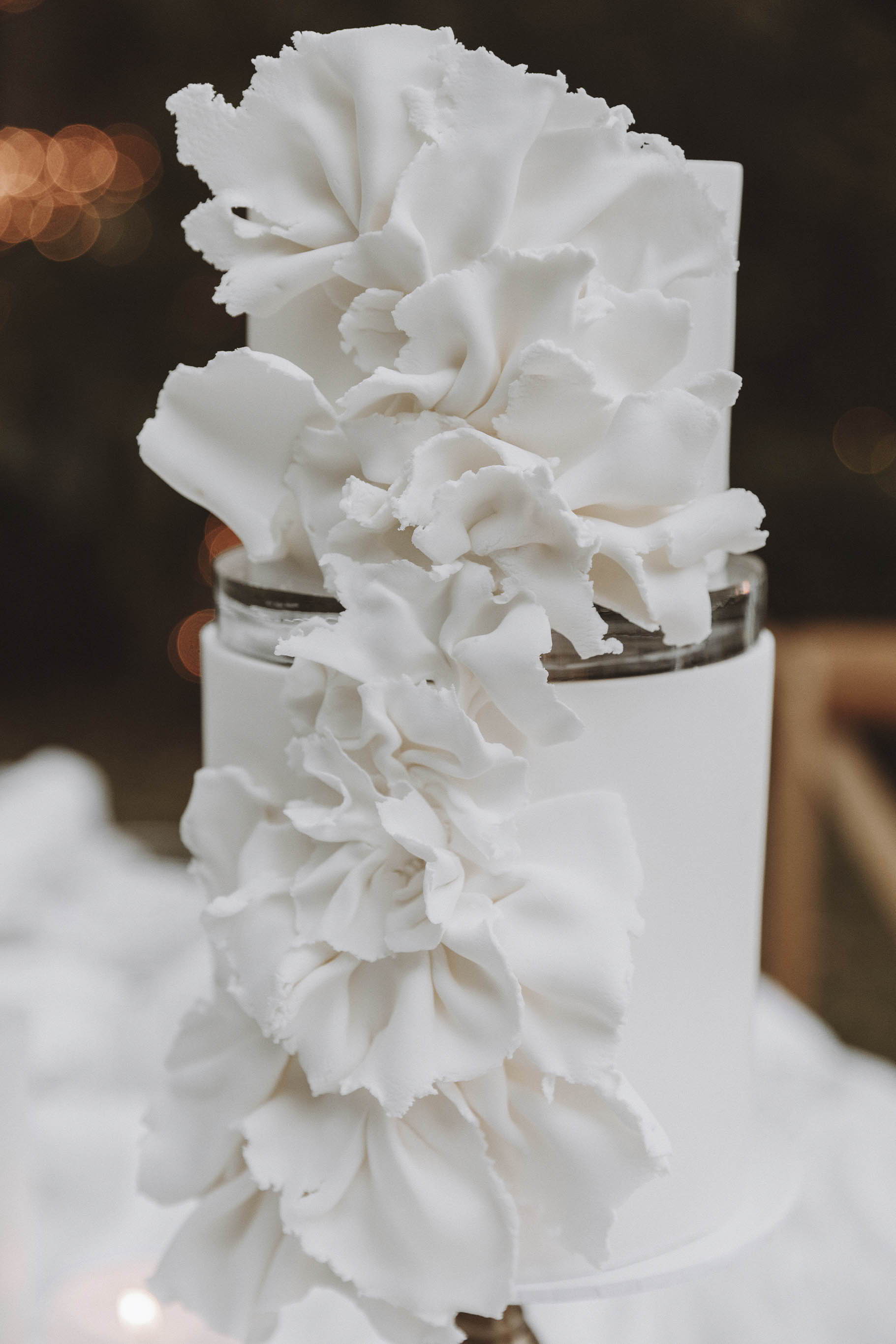 White wedding cake with white floral arrangement on top