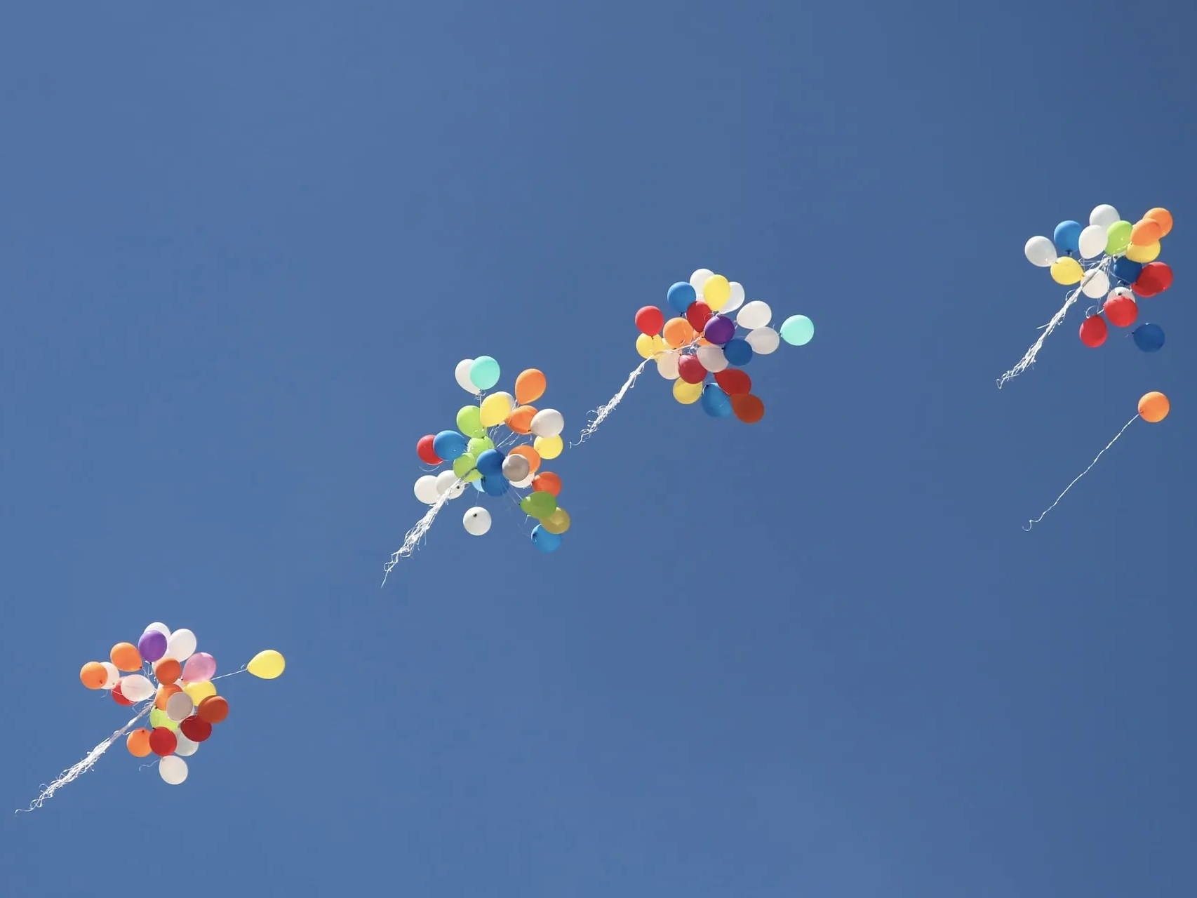 Four bundles of balloons floating away