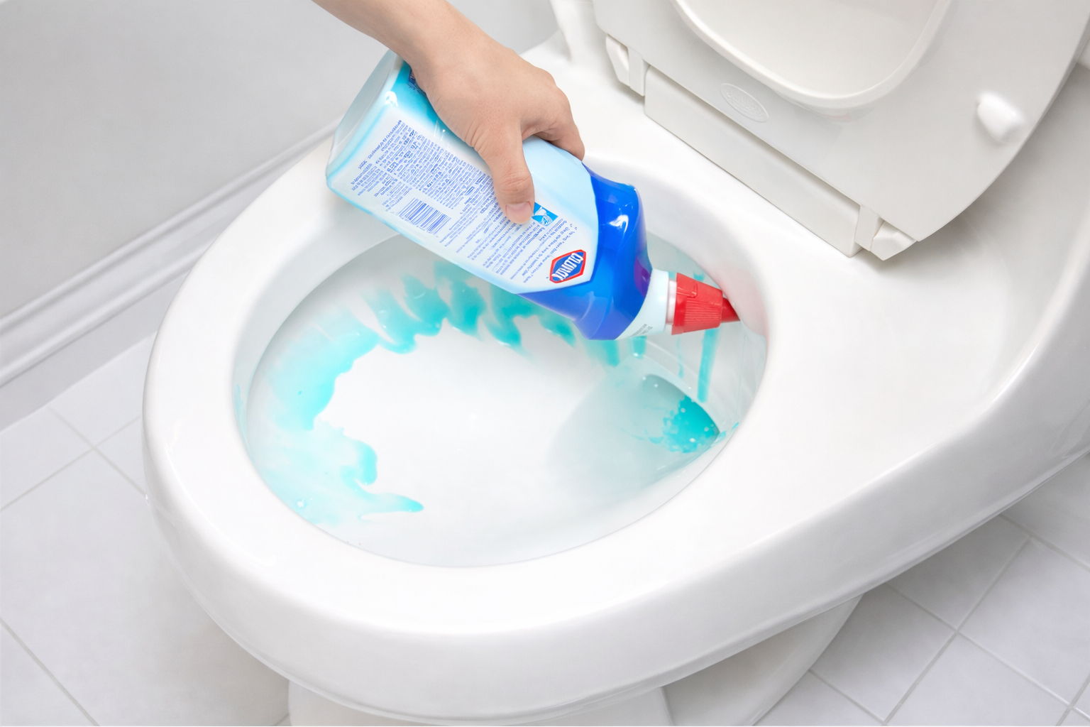 Person pouring blue toilet cleaner into a white toilet bowl.