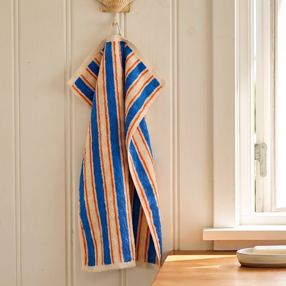 Striped kitchen towel hanging on a wall near a window.