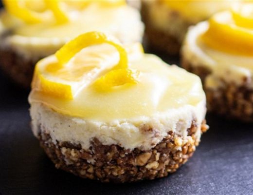 Mini lemon cheesecakes with a graham cracker crust and lemon slices on top.