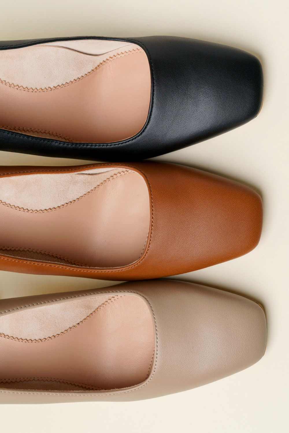 Three pairs of square-toed shoes in black, brown, and beige.