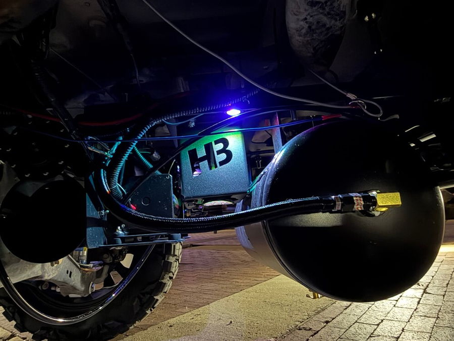 Nighttime undercarriage view Stealth Spare Tire Delete air tank and illuminated HornBlasters HB compressor enclosure with blue accent lighting on Troy's 2018 Ford Expedition gallery photo 2
