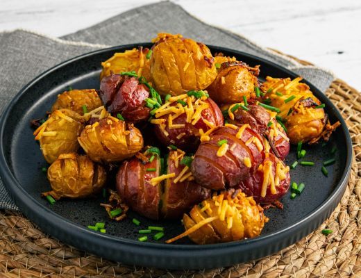 A plate of bacon-wrapped potatoes topped with cheese and herbs.