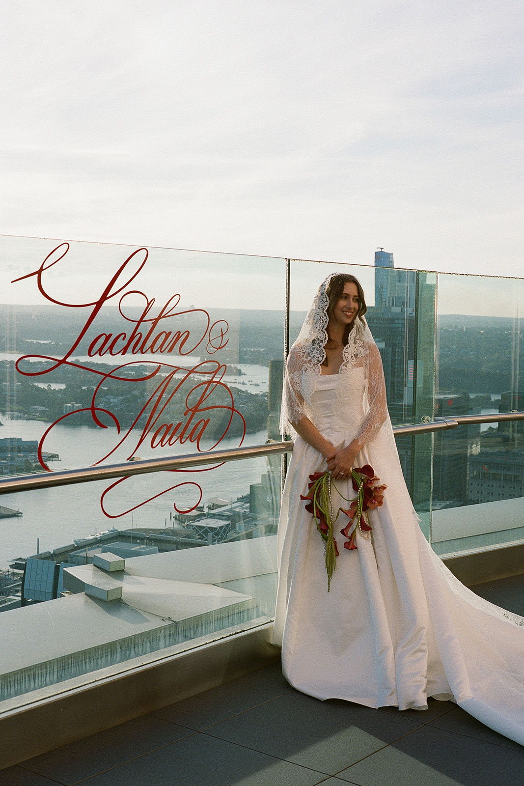 Bride in a white dress with flowers, standing on a balcony.