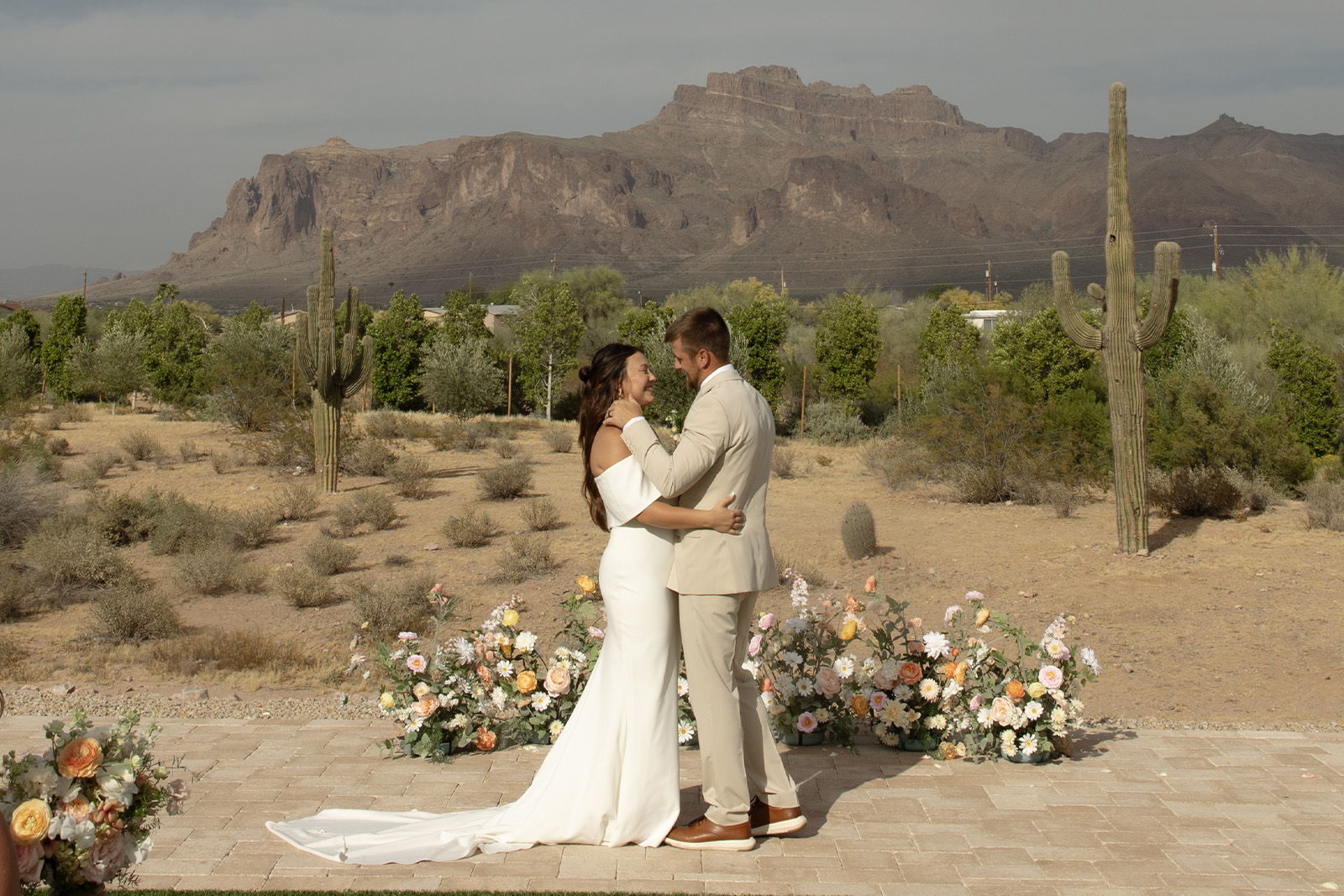 Couple embracing during wedding ceremony in a desert landscape.