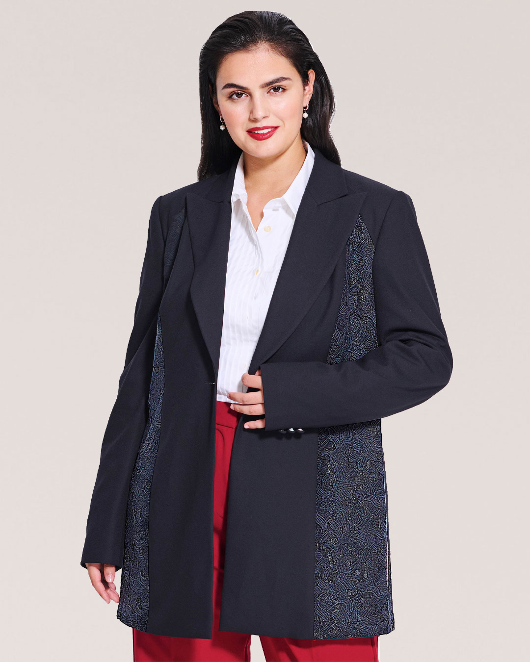 Woman wearing a stylish black blazer over a white shirt and red pants.