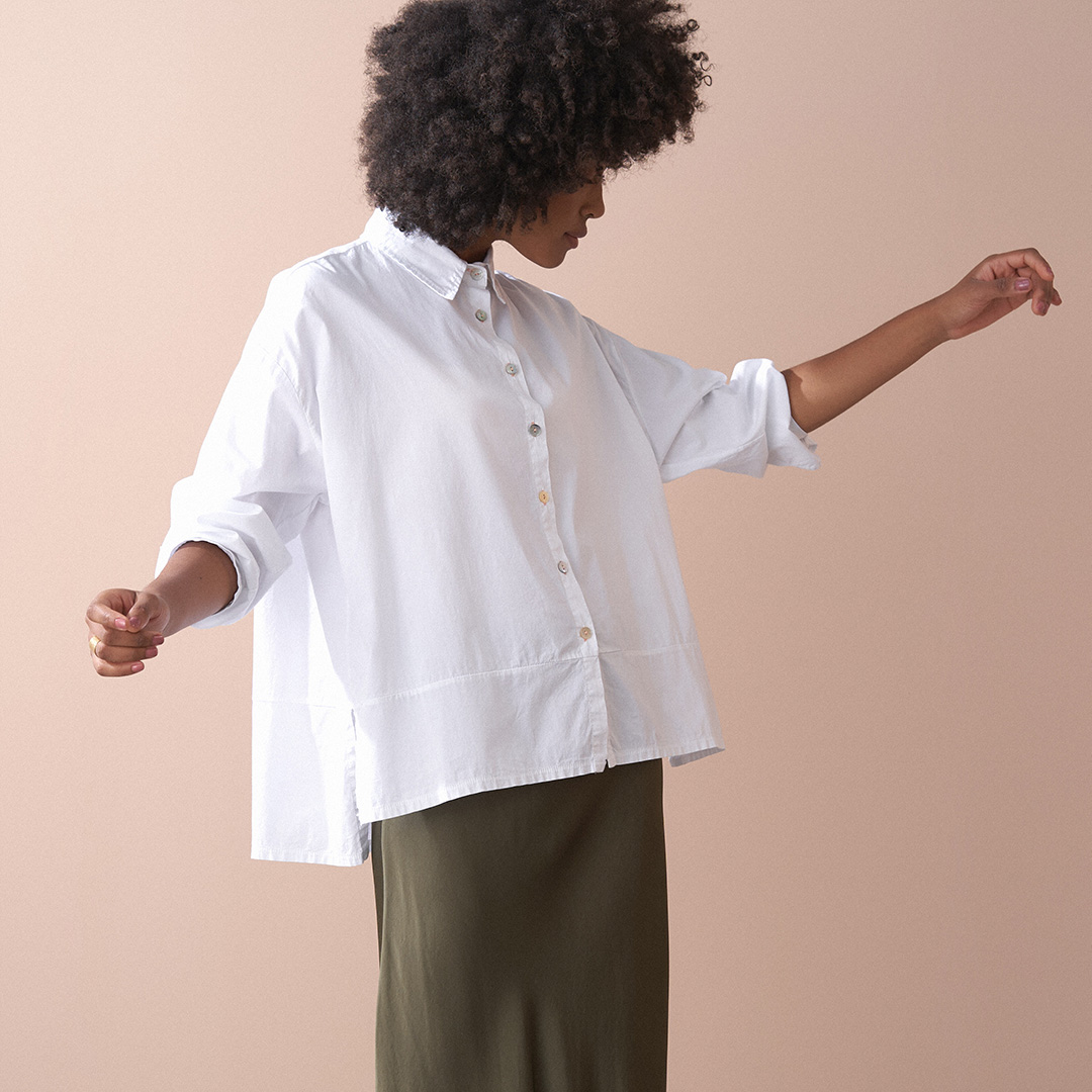 Woman wearing a white, boxy cotton shirt with satin skirt