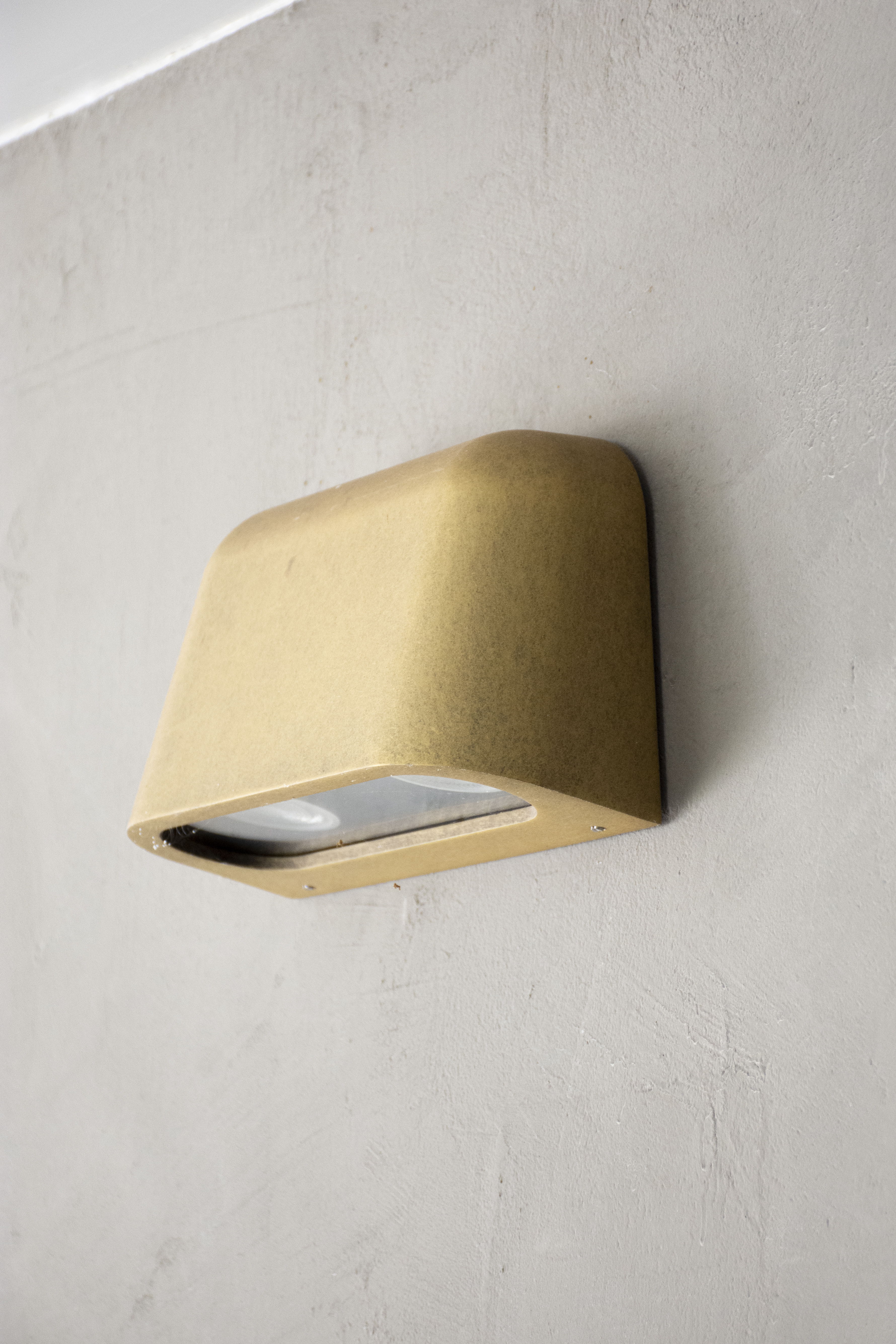 Wall-mounted light fixture with a minimalist design on a textured wall.