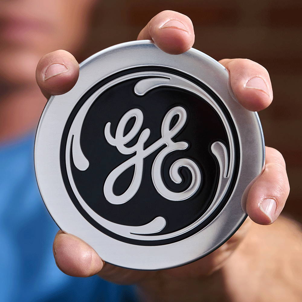 Image of man holding a GE logo badge