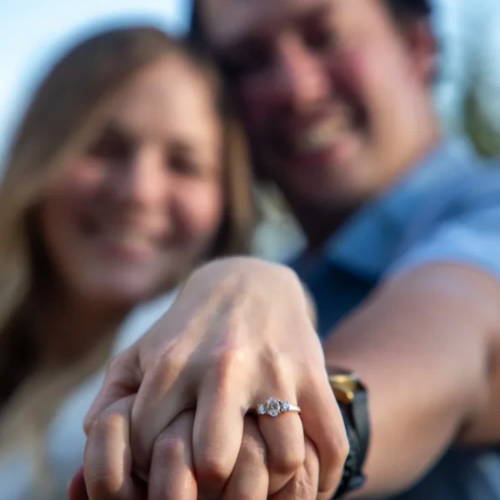 Engaged couple showing off stunning three stone engagement ring