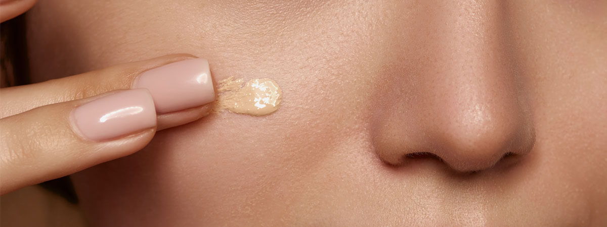 Person applying a foundation with SPF on their cheek.