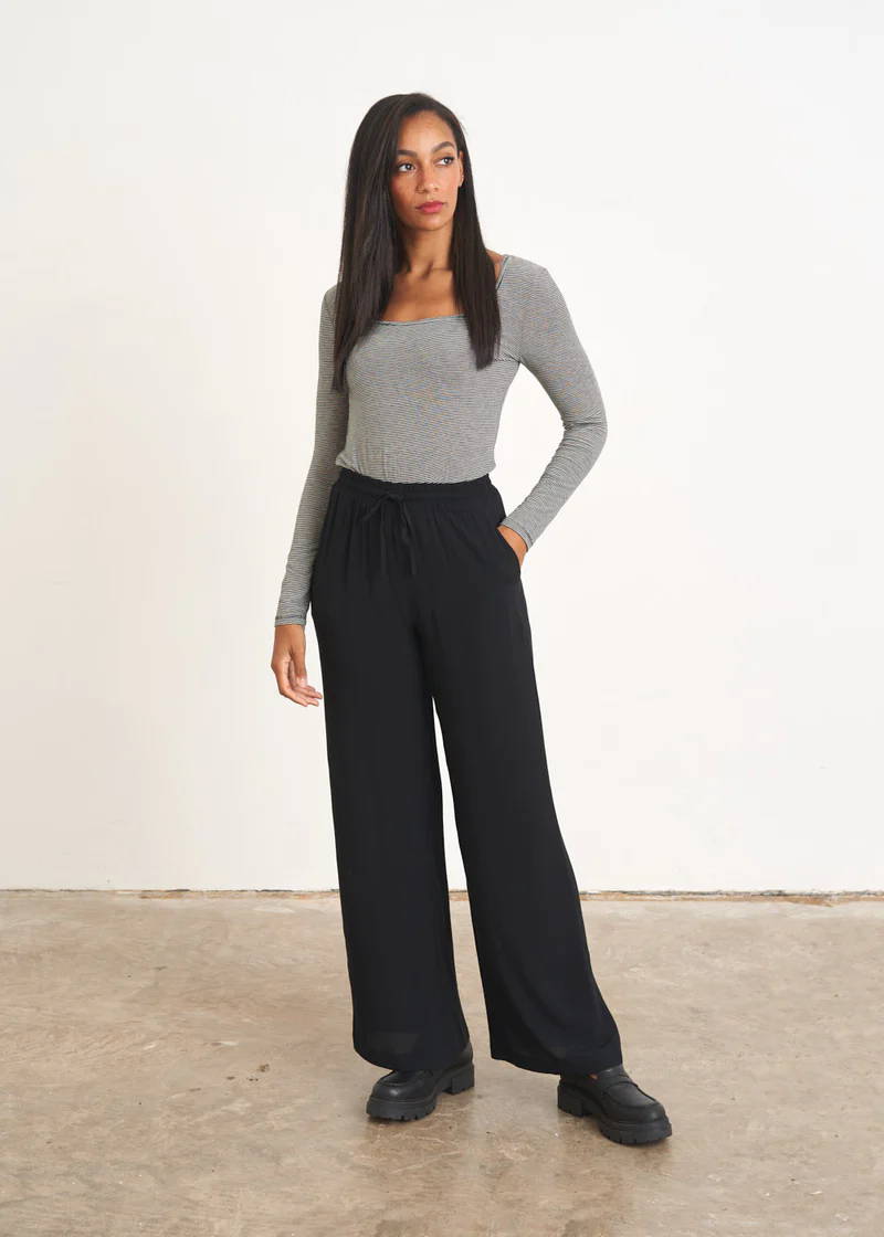 A model wearing a long sleeved striped top with black wide leg trousers and black boots