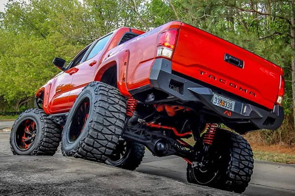 Rear-quarter red lifted Toyota Tacoma red springs black bumper off-road tires trees Billy's 244K Nightmare Edition gallery photo 3