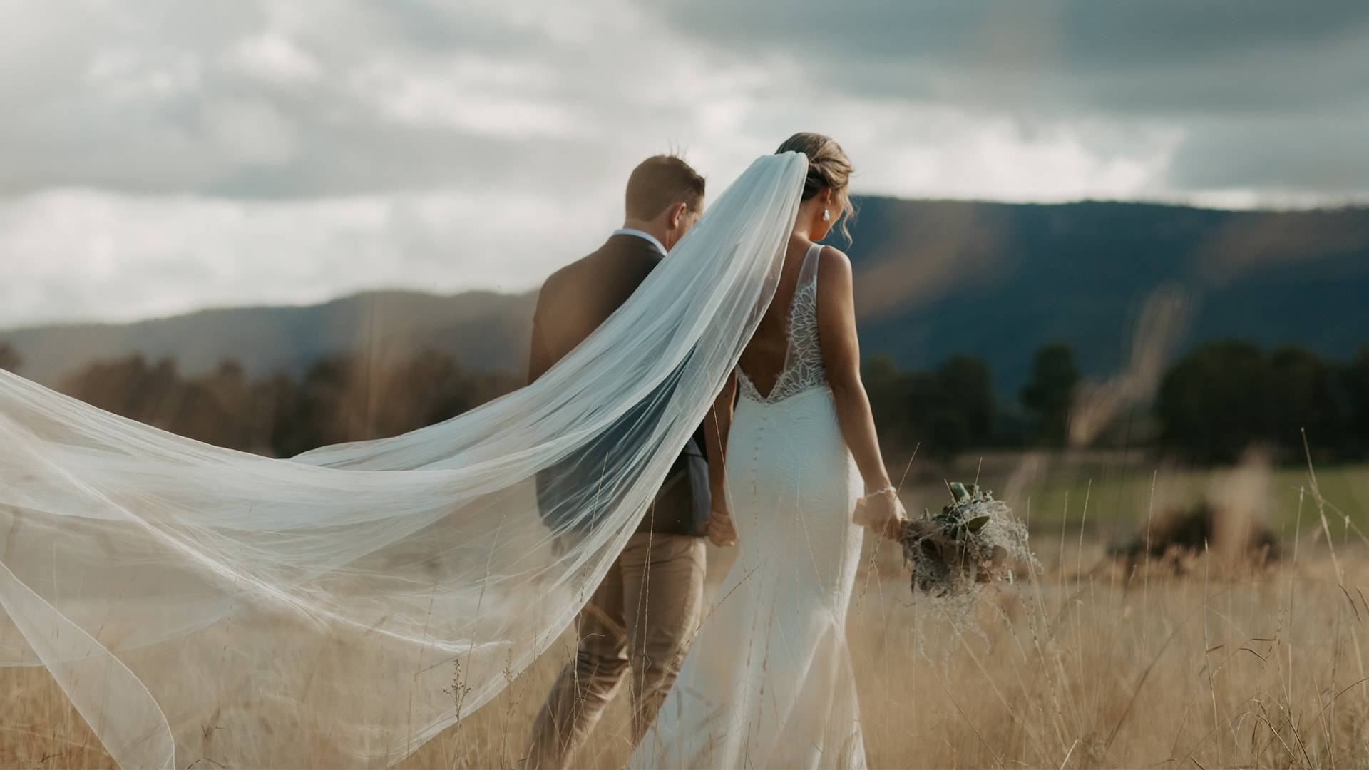 Grace Loves Lace Bride wearing the Henri veil walking through a grass field