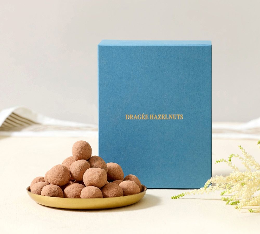 A blue box next to a plate of chocolate truffles.