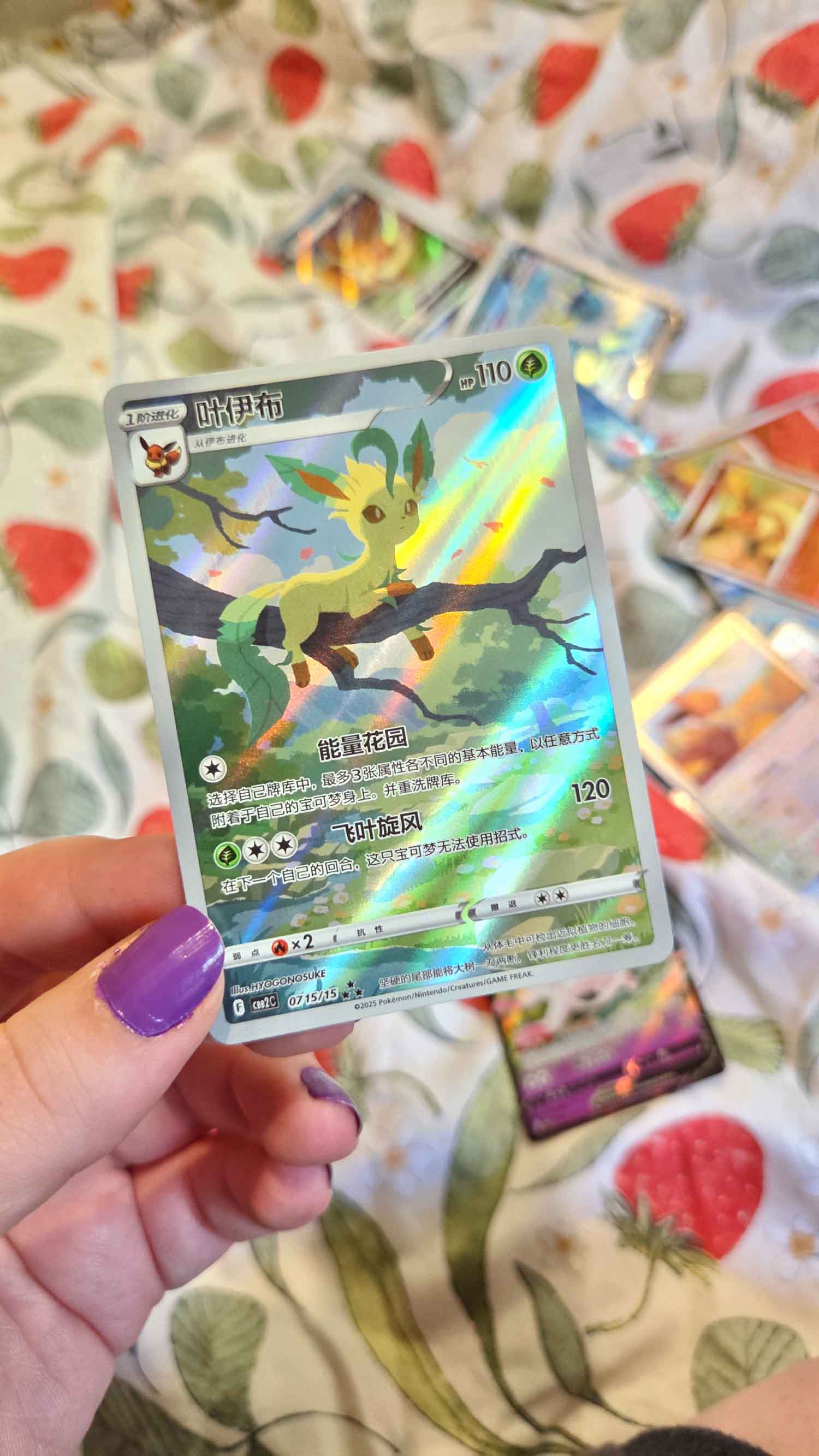 A hand holding a holographic trading card on a patterned surface.