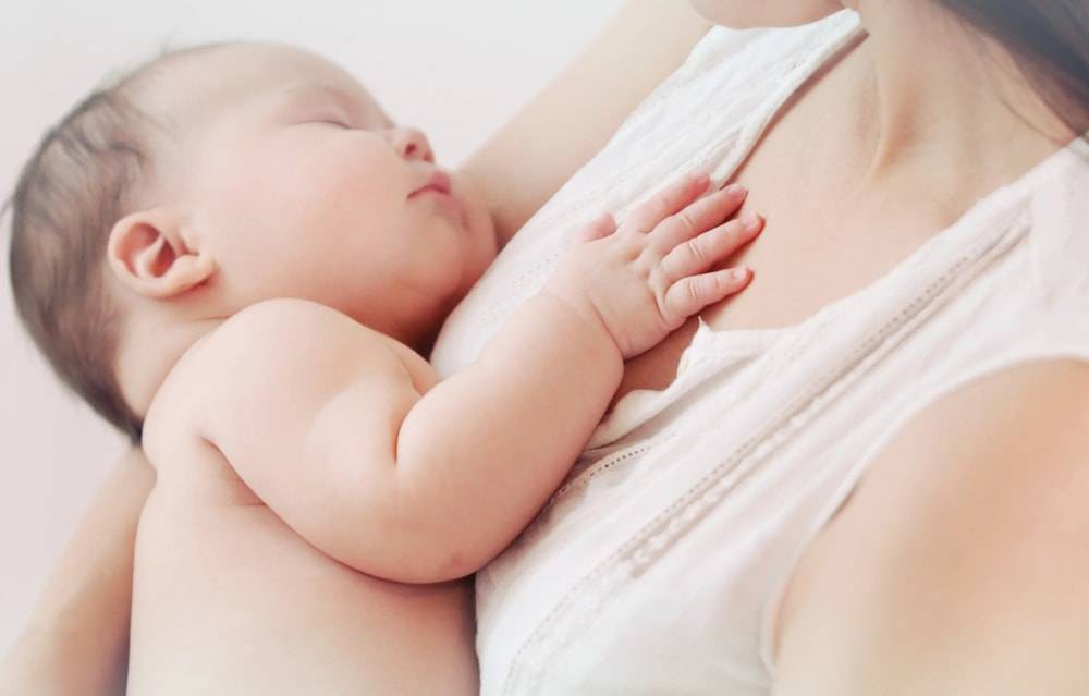 Photo of a mother holding up her sleeping baby