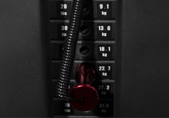 Weight machine selector with red knob and black spiral cable.
