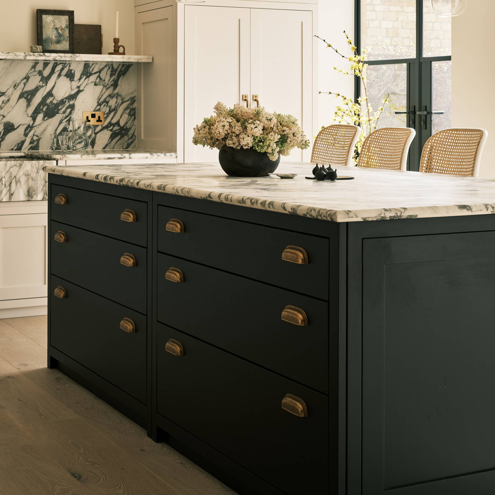 Navy kitchen designed by Laura Butler-Madden with brass cup pulls, marble worktops and wood floor
