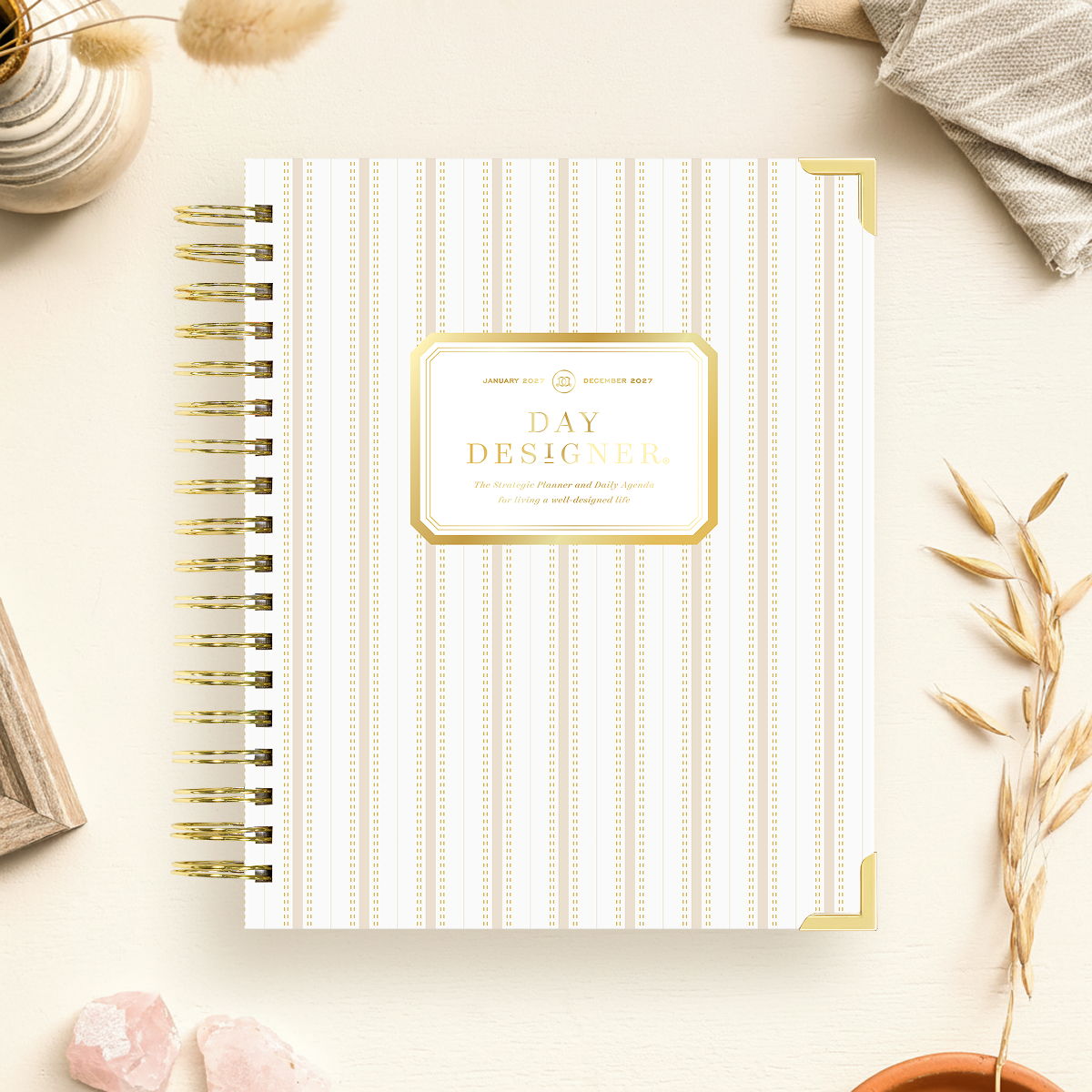 2027 day designer planner featuring beige and gold vertical stripes, gold binding on a beige background