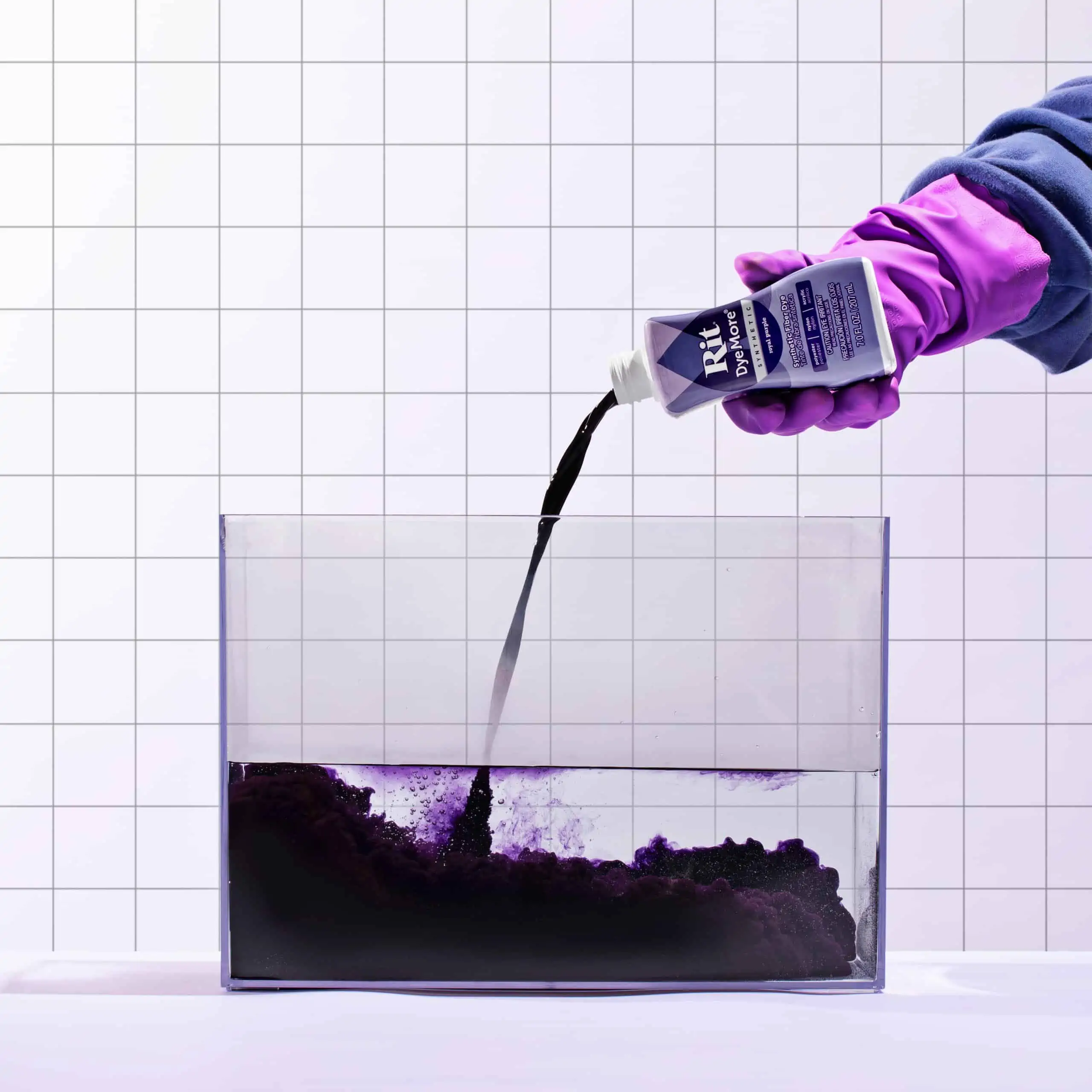 Person in gloves pouring liquid into a transparent container.