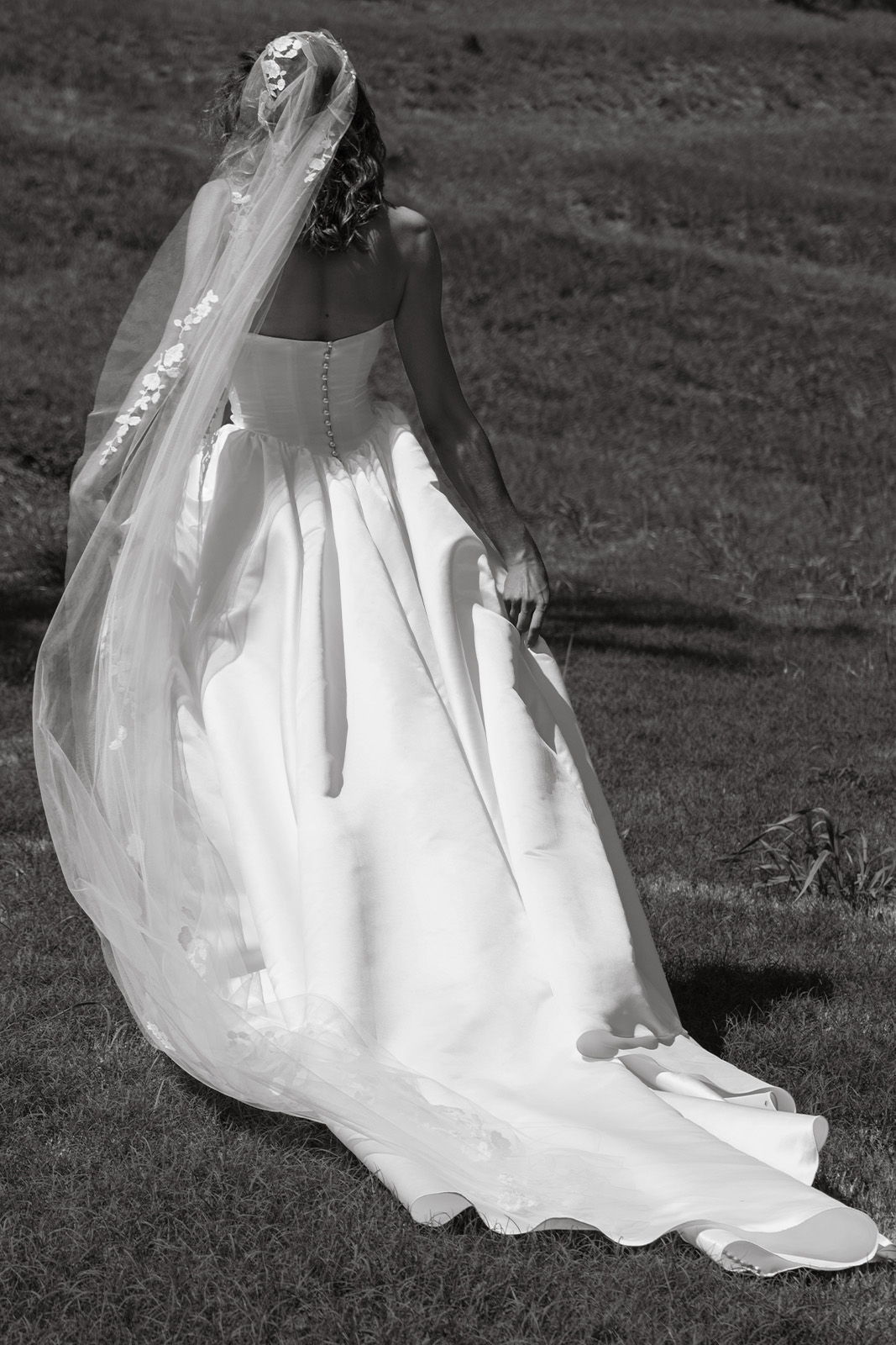 Bride in a wedding dress with a veil, outdoors in black and white.
