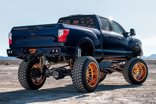 Rear three-quarter blue lifted Nissan Titan copper wheels custom bumper desert CaliCustomsOKC 2017 Titan Conductor's Special 544K Nightmare Edition customer install gallery photo 3