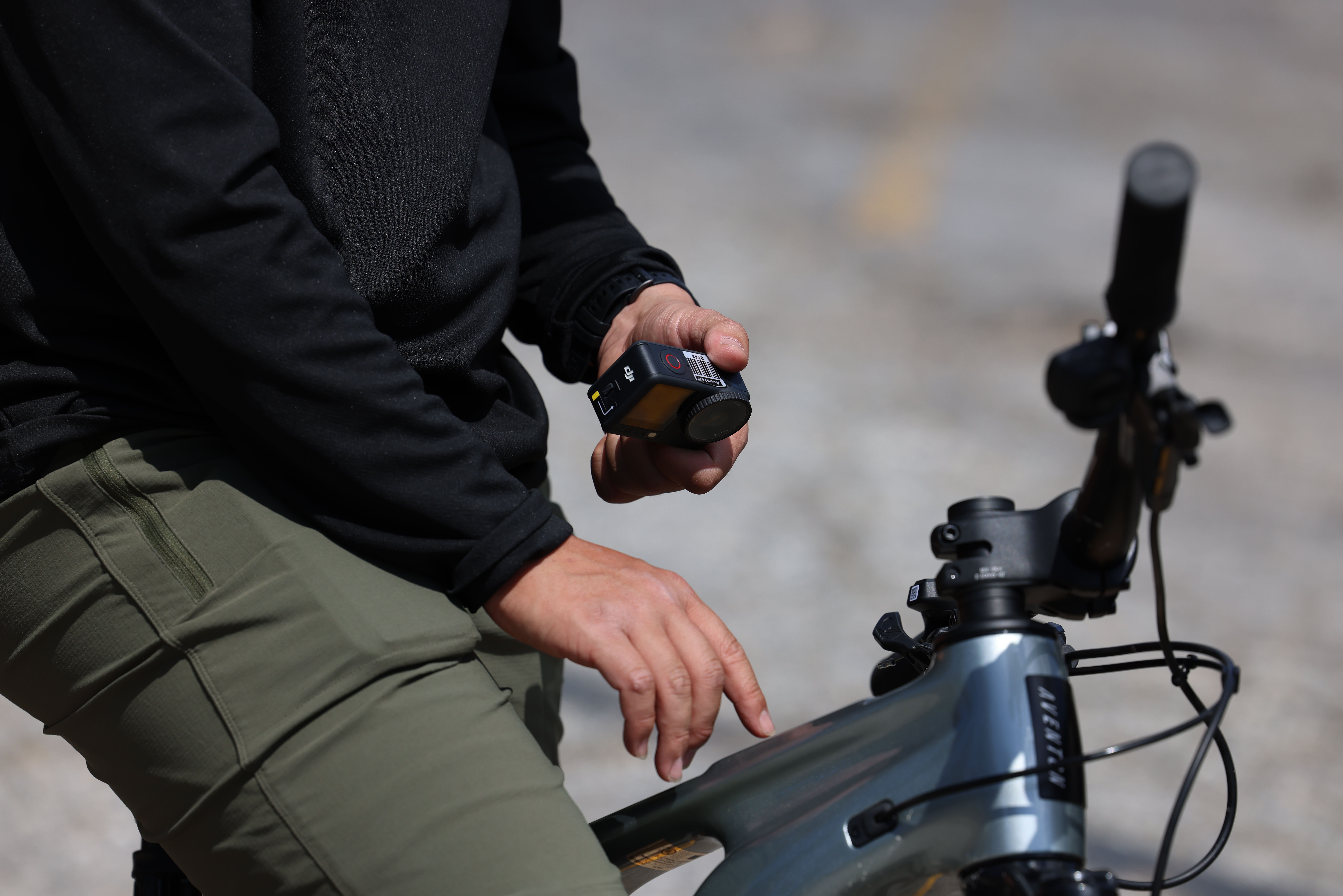 Person holding a device while sitting on a bicycle.