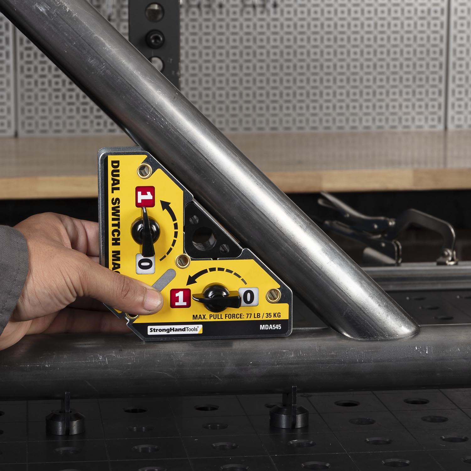 A hand holding a yellow angle finder against a metal frame.