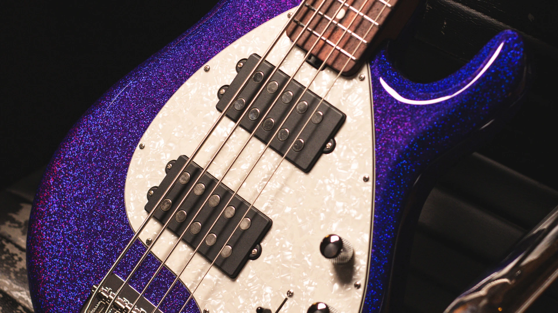 Close-up of a purple Music Man StingRay 5 Special bass guitar with white pickguard and black humbucker pickups.