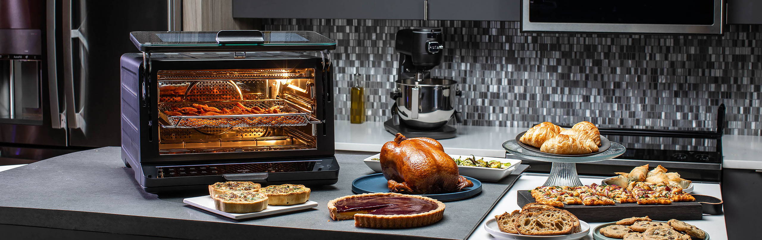 GE Profile Smart Oven on counter with several delicious foods surrounding it