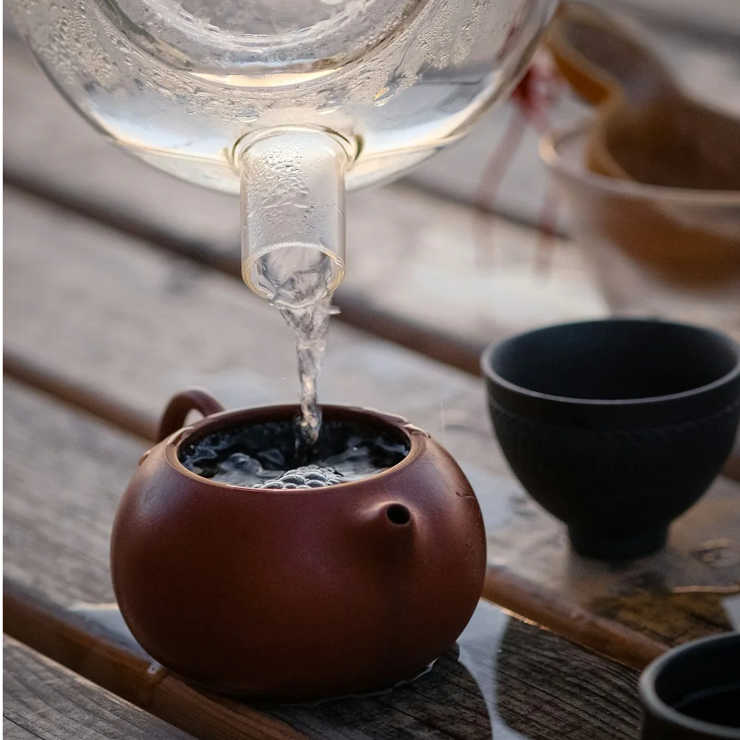 a hand pouring a liquid into a glass container