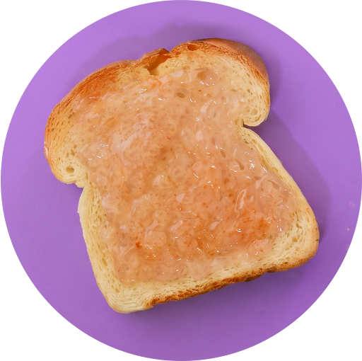 Slice of toasted bread topped with Tastefully Simple Champagne Jelly on a purple background.