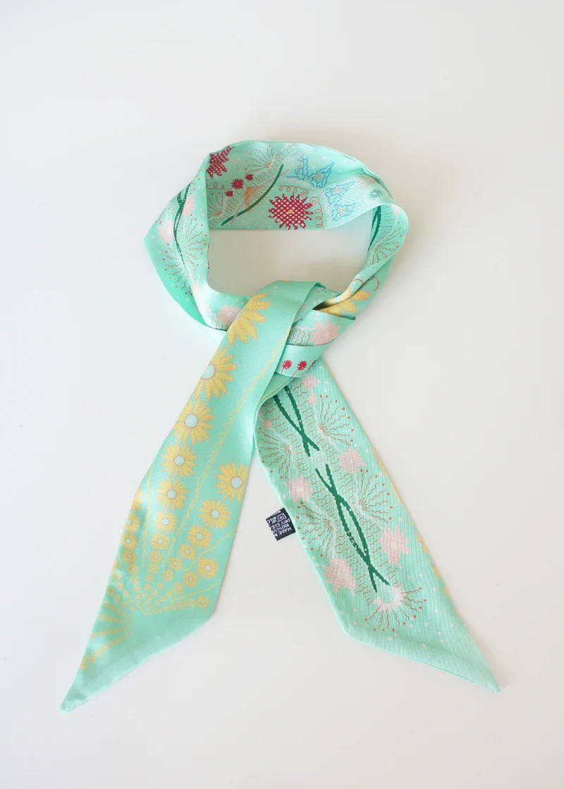 A light blue silk neck scarf with a botanical print