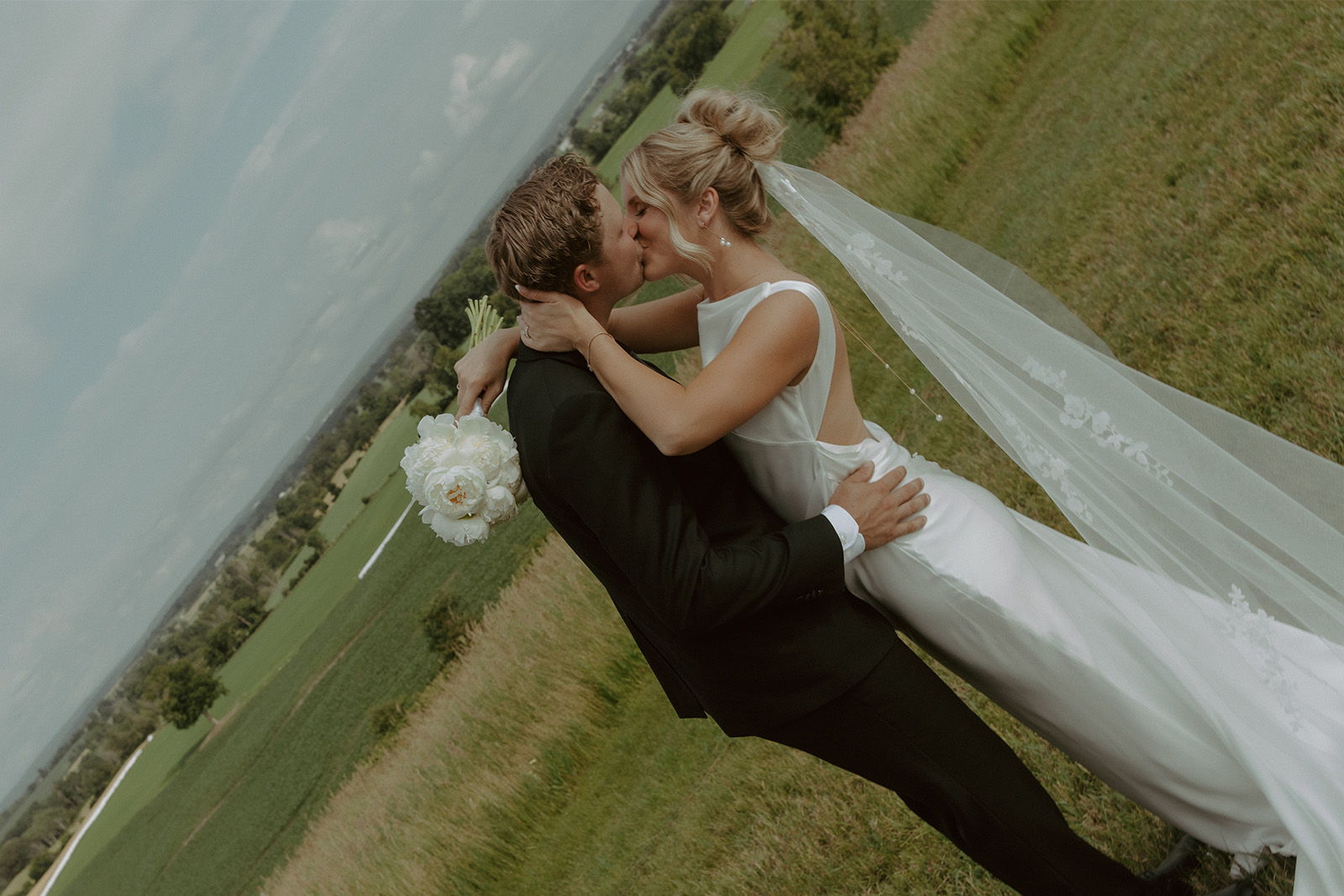 Bride and groom embracing in a picturesque outdoor setting.