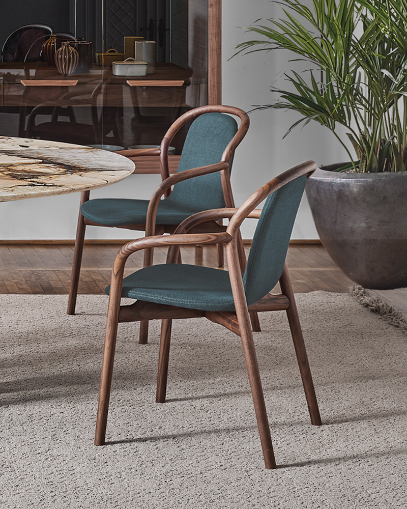 A maroon upholstered Porada chair with a wooden frame and curved backrest.