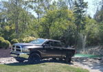 Side view of gray RAM 2500 parked beside pond with fountain in landscaped yard