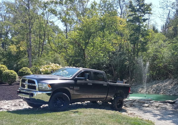 Side view of gray RAM 2500 parked beside pond with fountain in landscaped yard