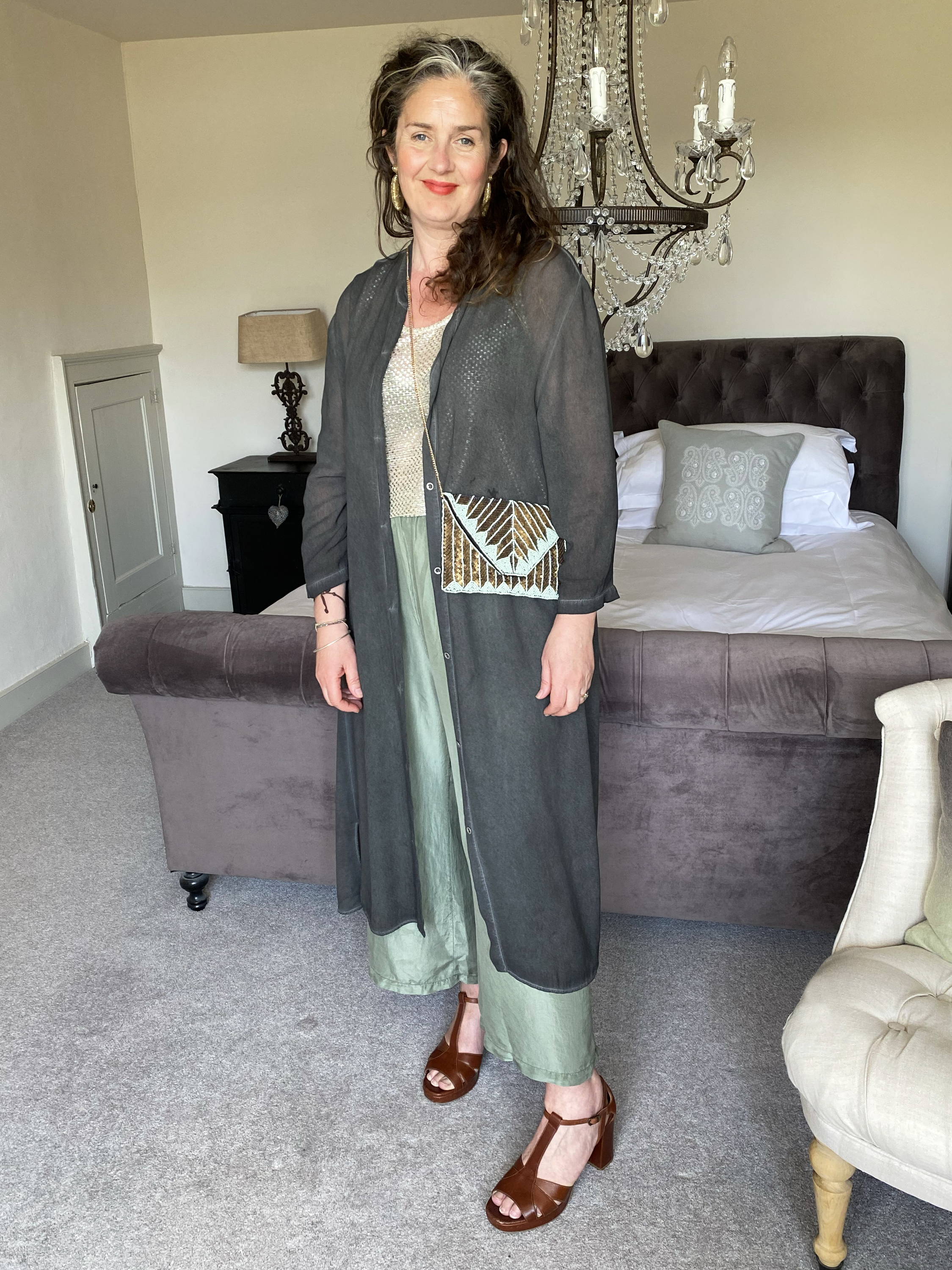 Emma Vowles ready for a 50th birthday bash wearing green cropped silk trousers, a sparkly cream top and a black semi-sheer overshirt paired with some heels and a sequin over shoulder clutch bag