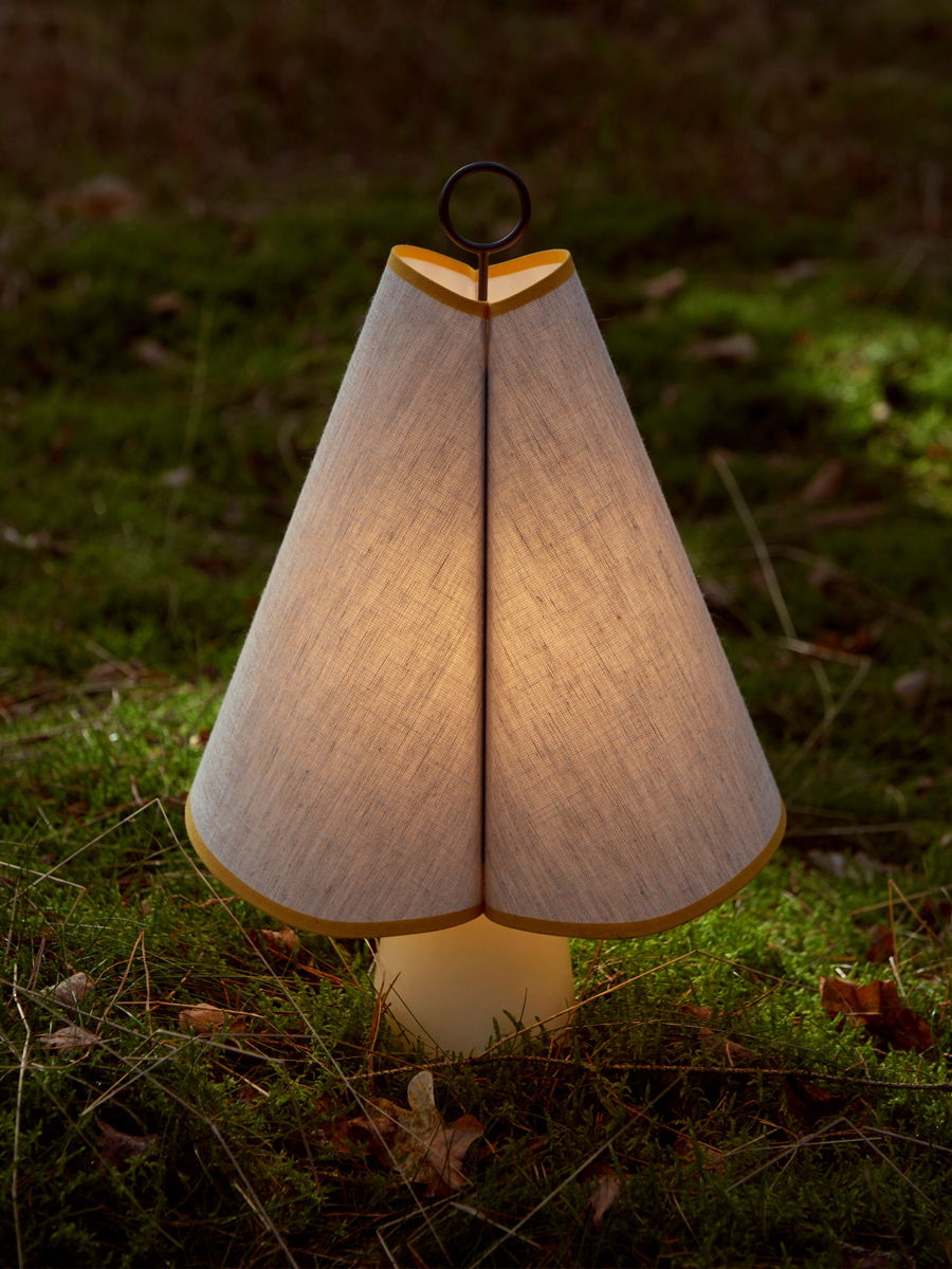 A glowing lamp with a cone-shaped shade on green grass.