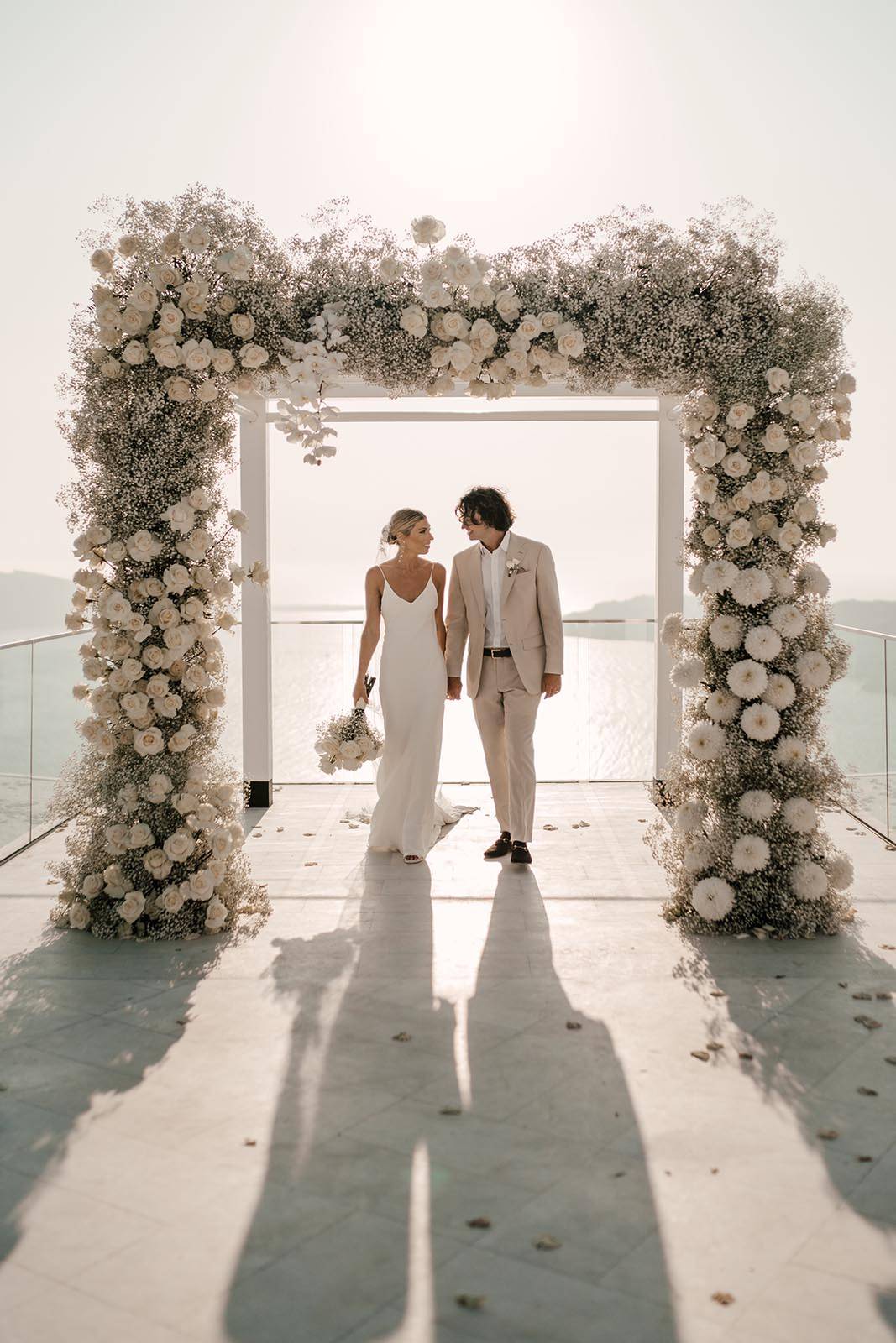 Bride and groom underneath square shaped floral arbor